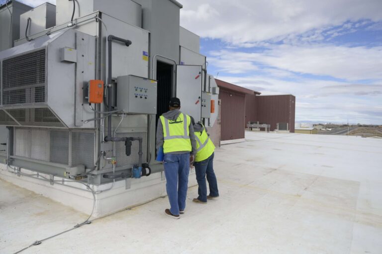 Two Chugach employees work on a mechanical system at a military base